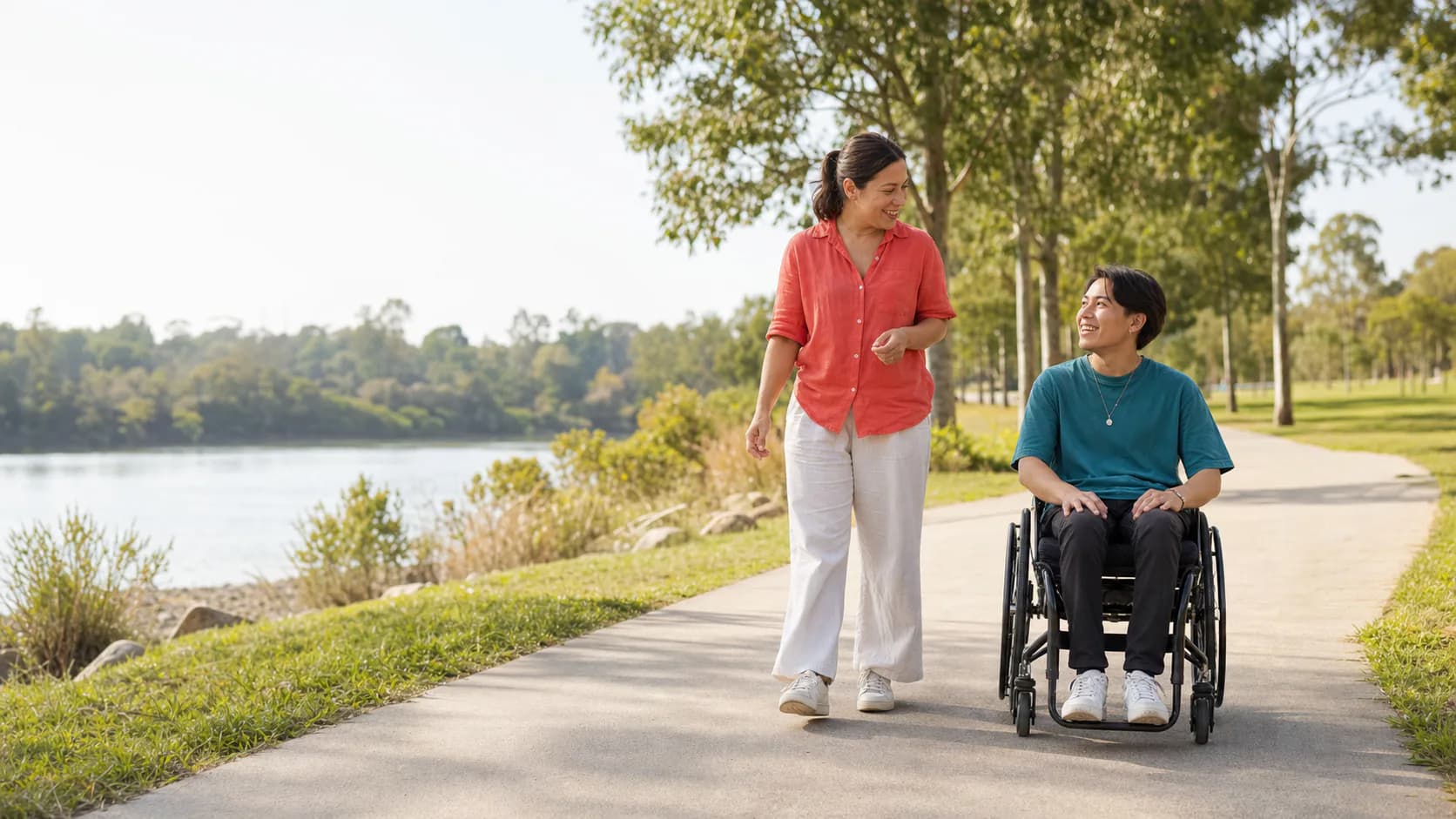 Illustrative models, a mentor and young wheelchair user, talking in a sunny Western Sydney park
